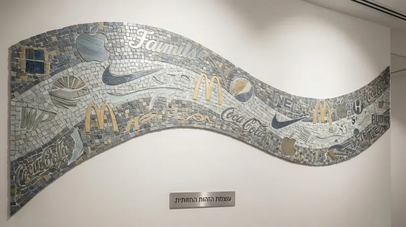 פסיפס אומנותי על קיר המציג לוגואים של מותגים בינלאומיים כמו אפל, נייקי ומקדונלד'ס, עם שלט מתחתיו הנושא את הכיתוב "עוצמת הזהות החזותית".